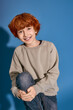 © Bliss - Stylish little boy with playful grin poses against a vibrant blue background in casual attire