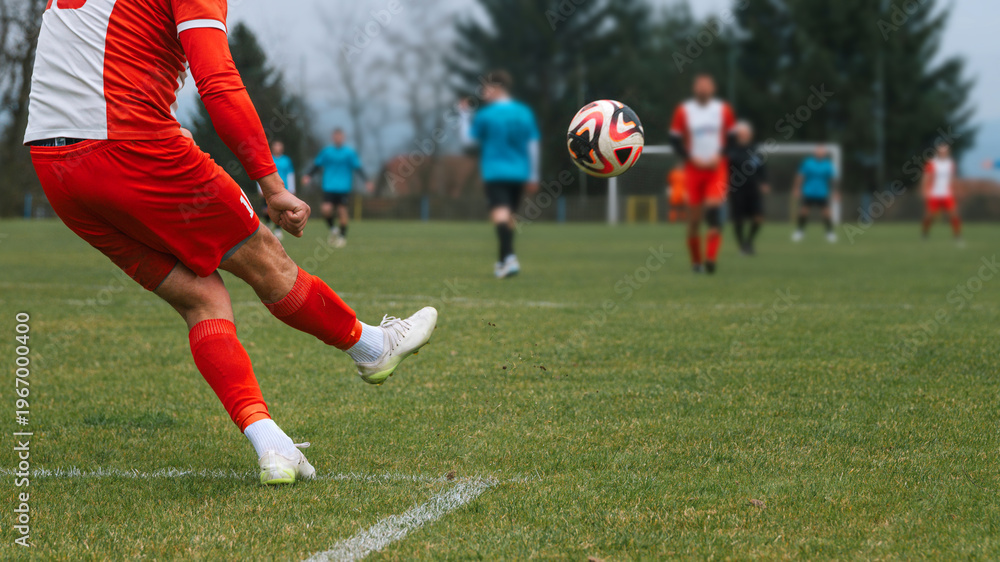 Player kicks soccer ball on a grass field during an amateur village ...