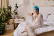 © LIGHTFIELD STUDIOS - Vibrant young woman enjoying a cozy morning with coffee in a stylish bedroom setting