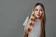 © SHOTPRIME STUDIO - Young woman with long straight hair and casual white t-shirt posing against gray studio background looking sideways with thoughtful expression and natural makeup.