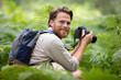 © auremar - young man with backpack taking a photo of forest