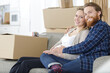© auremar - couple expecting baby sat on sofa surrounded by cardboard boxes