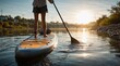 © OlegKovalevich - Woman practicing stand up paddle boarding on river at sunset. Athlete balancing on sup board with paddle. Outdoor water sport activity in summer. Recreation, fitness and healthy lifestyle.