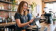 © Vasiliy - Smiling female barista using tablet POS system at coffee shop counter. Happy young woman working register in modern cafe with exposed brick wall. Small business owner concept