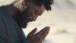 © Alper AI - Man with beard and dreadlocks praying with eyes closed in a desert landscape