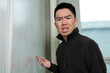 © fotolite - A young Asian male student looks directly at the camera exasperated while gesturing toward a whiteboard with math equations, ideal for math difficulties, STEM challenges, or student struggle concepts.