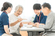 © buritora - Female patients and male and female caregivers performing bean-grabbing exercises at nursing homes, hospitals, and rehabilitation centers.