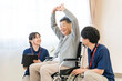 © buritora - A senior woman in a wheelchair doing exercises as part of her rehabilitation, accompanied by female physical and occupational therapists.