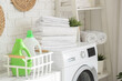 © Pixel-Shot - Stack of clean bed sheets on washing machine in laundry room