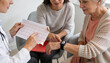 © Breezze - Female doctor reviewing ECG test results with senior patient and daughter in clinic, cardiologist explaining heart health data during medical consultation