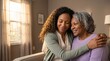 © OlgaNeuroArt - Young African American woman hugging an elderly woman at home. Multi-generational family support and care concept. Daughter embracing senior mother in a living room