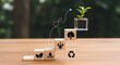 © MUHARDING - A small potted plant grows on wooden blocks with eco-friendly symbols on a table.