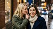 © Irfan - Blonde woman whispering a secret into brunette friend's ear in a city at night