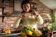 © Davor - Woman photographing fresh vegetables in home kitchen