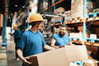 © Davor - Warehouse workers lifting boxes in distribution center aisle