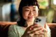 © Davor - Smiling woman using smartphone at home