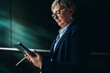 © BullRun - Senior woman in formal attire interacting with tablet and stylus, reflecting digital literacy, tech empowerment, and concentration in mobile business workflows.