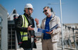 © qunica.com - Two professionals discuss plans and blueprints at an outdoor construction site. The colleagues review project documents and inspect the building area together.
