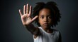 © Olga Ко - Retrato dramático de criança negra fazendo sinal de pare com a mão, conceito contra abuso, bullying e violência