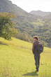 © Yar - Vertical view of a man with a backpack walking on a sunny green mountain slope in Asturias, Spain