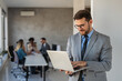 © NDABCREATIVITY - Confident banking professional in modern office holding laptop, symbolizing finance, investment