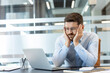 © Liubomir - Stressed businessman working on laptop experiencing burnout, holding his face in frustration with a corporate workload causing emotional pressure and mental exhaustion in the modern office
