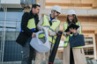 © qunica.com - Construction engineers wearing hard hats and reflective vests review blueprints and a tablet at a building site. The team consults plans and digital drawings while discussing the project on site.
