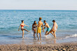 © Xavier Lorenzo - Friends splashing in the ocean on a sunny beach day, celebrating summer vacation with laughter, travel, and carefree togetherness during a joyful seaside getaway