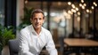 © Irina Ukrainets - Confident businessman in a modern office setting. He is dressed in a smart white shirt. The background features stylish decor and warm lighting. This image conveys professionalism. AI