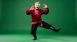 © Margarita Ratatosk - Mature man performing folk dance in national costume, standing on one leg. Dynamic movement on green screen for easy removal.