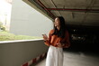 © PaeGAG - Young asian woman holding smartphone standing in parking lot