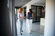 © Zoran Jesic - Two businesswomen walking and talking in modern office hallway