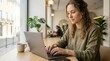© Eve - Focused young woman working on laptop in modern coffee shop, professional freelancer multitasking, student studying online, remote workplace with minimalist interior and daylight.