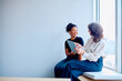© we.bond.creations - Diverse businesswomen discussing work using a tablet while sitting in a modern office space, fostering mentorship and teamwork