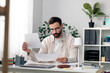 © MexChriss - Man in glasses reviewing business documents at home office