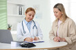 © New Africa - Smiling woman having appointment with cardiologist at table in clinic