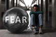 © New Africa - Fear making life harder. Sad man chained to huge weight against blurred background. Negative emotions