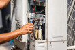 © iPoguz - Technician performing maintenance service on home air conditioning system, Close up of hands using allen key to adjust valve on outdoor unit, HVAC contractor repairing a split system air conditioner