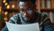 © Maryna - Man in glasses reads document. Person concentrates on paper text in cafe or library. Male student studies book pages, gains new knowledge. Focused man learns information indoors.