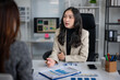 © apichat - Businesswoman discussing financial data with client in office