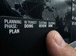 © Oma - Finger on a digital logistics display, monitoring global supply chain status from planning to delivery across various stages shown on an interactive world map interface