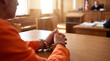 © Taras Roshchuk - A person in handcuffs sits at a wooden table in a courtroom. The individual waits for their turn to speak while a judge presides over the case. Light fills the room enhancing the setting