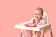 © Pixel-Shot - Cute little baby eating food in high chair against pink background