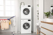 © Pixel-Shot - Interior of stylish laundry room with modern washing machines, drying rack and shelving unit