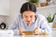 © Pixel-Shot - Young Asian woman doing steam inhalation at table in kitchen