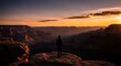 © huhu - A lone figure overlooks a majestic canyon at vibrant sunset