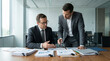 © Vera - Two men discussing finance in suits at a conference table