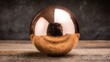 © MohamadIzzudin - Reflective Copper Sphere on Wooden Surface with Dark Background