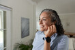 © Wavebreak Media - African American woman adjusting earbud while smiling by window at home, showing black smartwatch