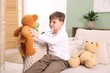 © New Africa - Little boy with his teddy bears on sofa at home
